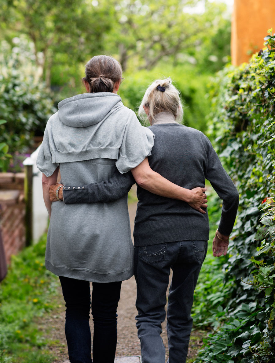 Two older women walk through the park arm in arm