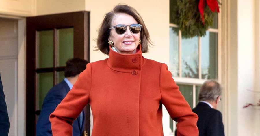 Nancy Pelosi walking out of the White House with her now famous red coat and sunglasses.