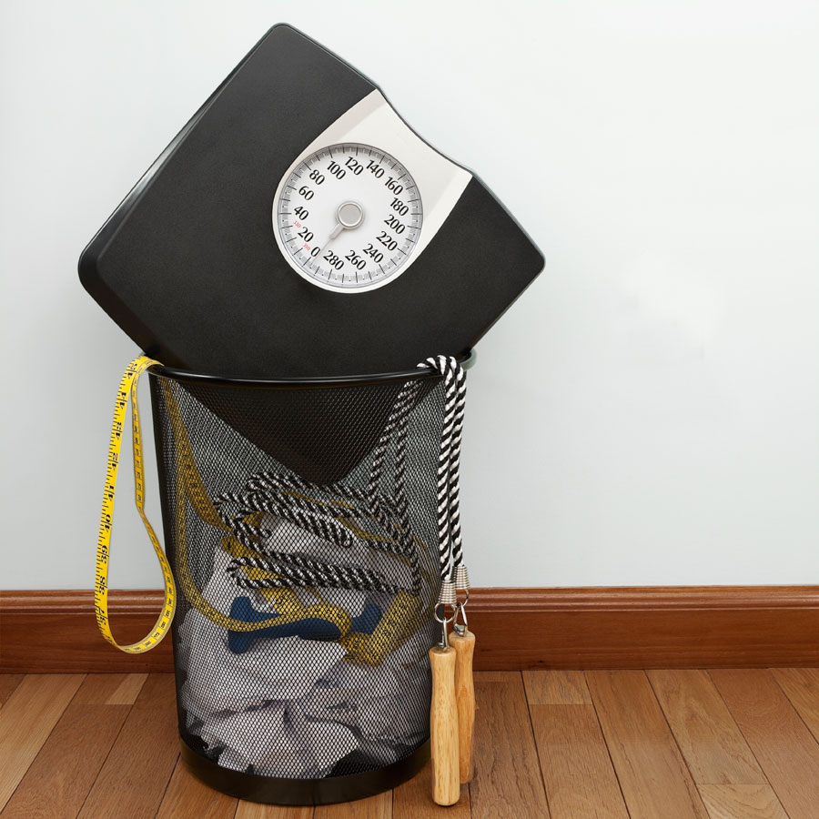 A scale and skipping rope shoved into a paper waste basket.