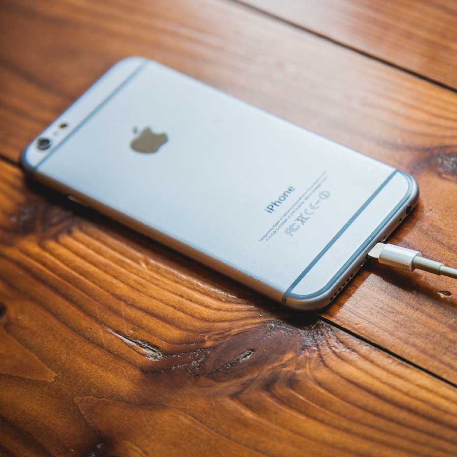 An iPhone laying face down on a wooden table.