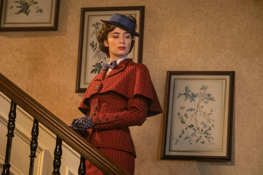 Mary Popins in her red dress and violet hat standing on the stairs.
