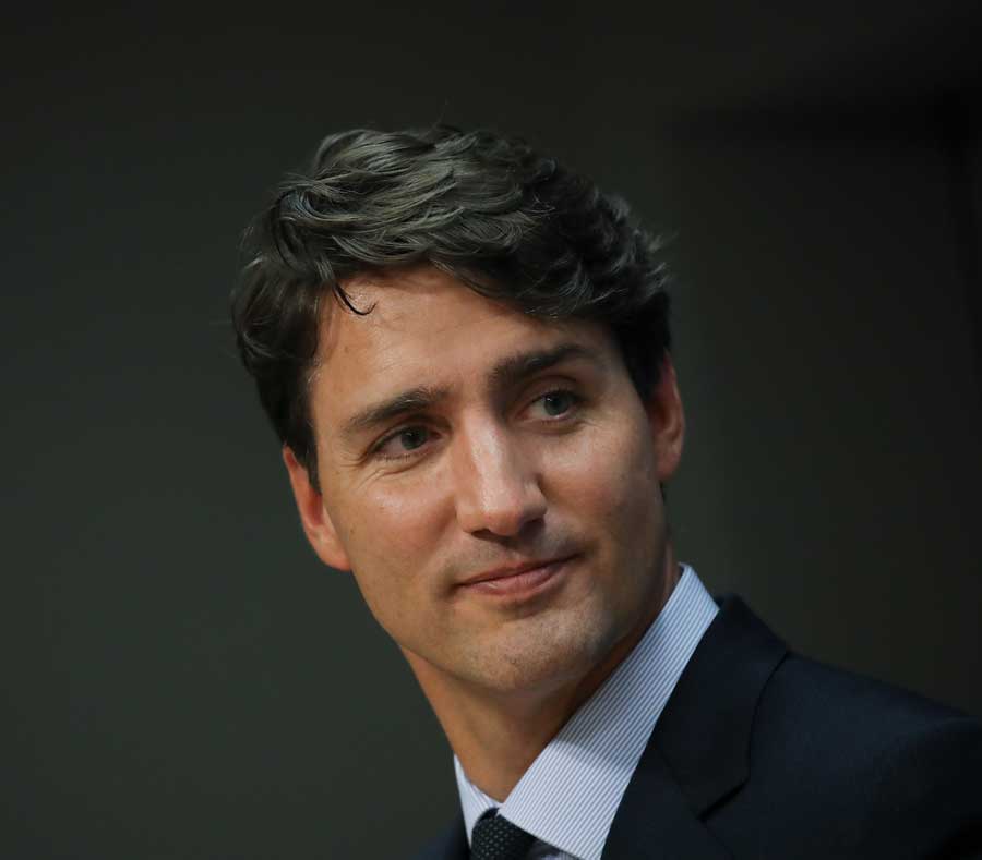 Trudeau on a black background smiling slightly.