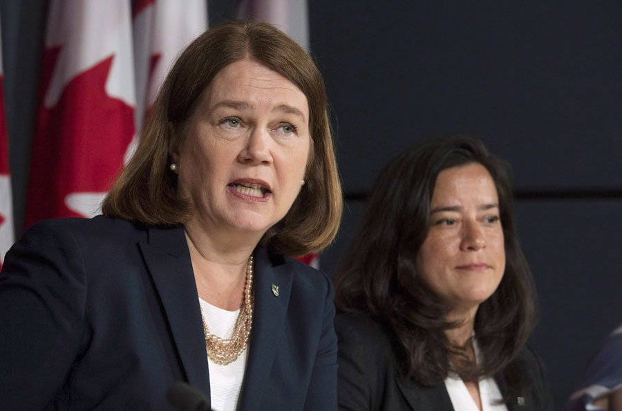 Jane Philpott and Wilson-Raybould side by side with a Canadian flag visible in the background.