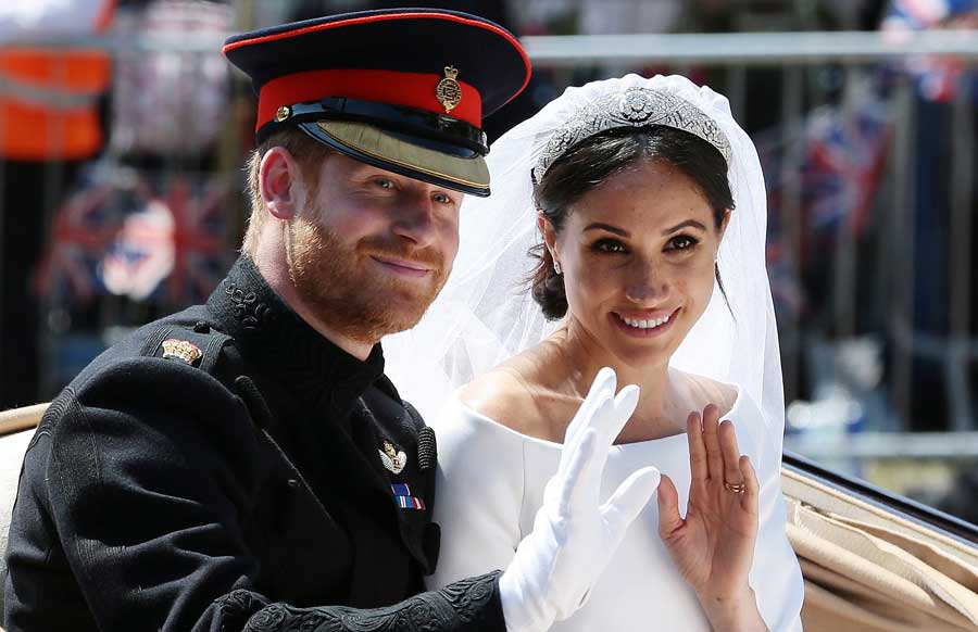 Meghan and Harry wave to fans from a horse and carriage on their wedding day.