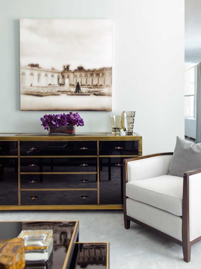 A living room with a long dresser chest and a painting of a church hanging above it.