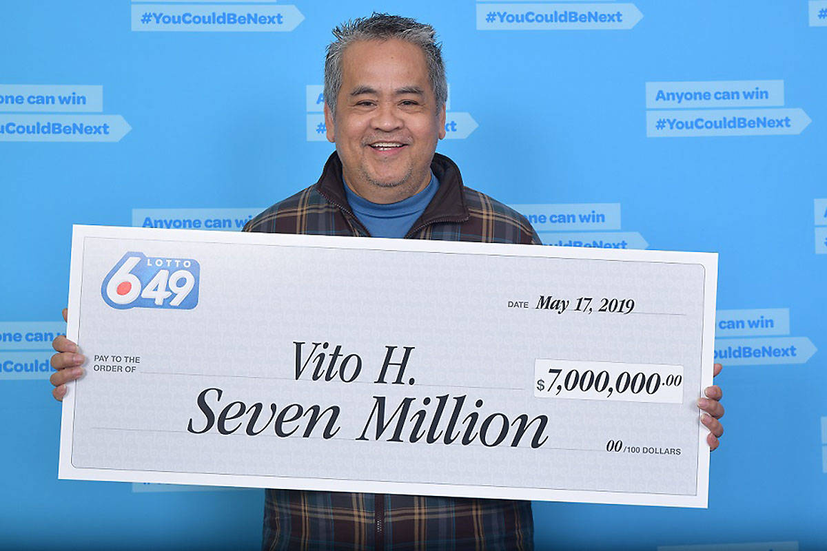 Vito Halasan smiles as he holds up his lottery check for $7 million.