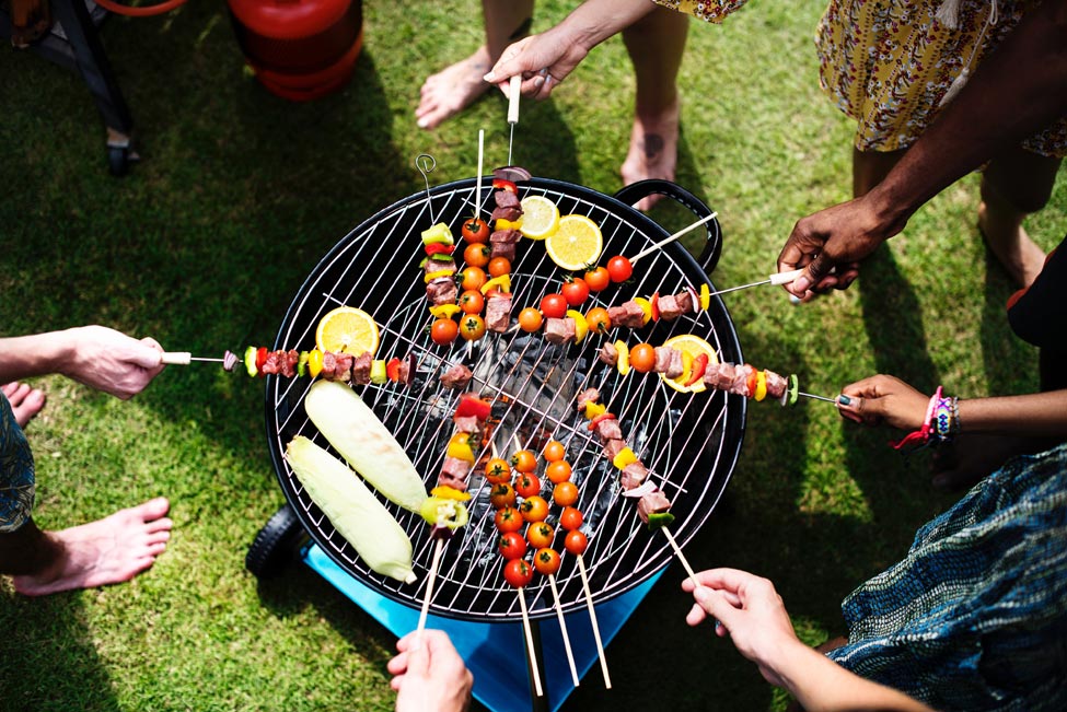 People standing over barbecue