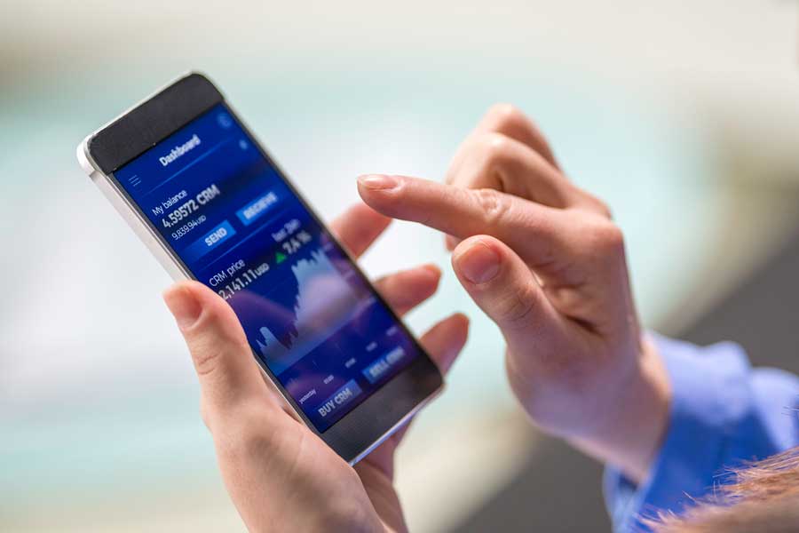 Man holding a phone displaying online banking screen.