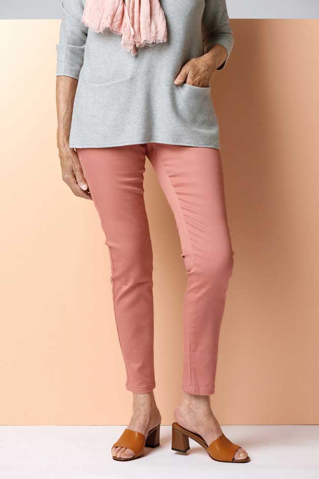 A woman wearing a grey top with a pink scarf and pink pants. The outfit completed with a brown shoe.