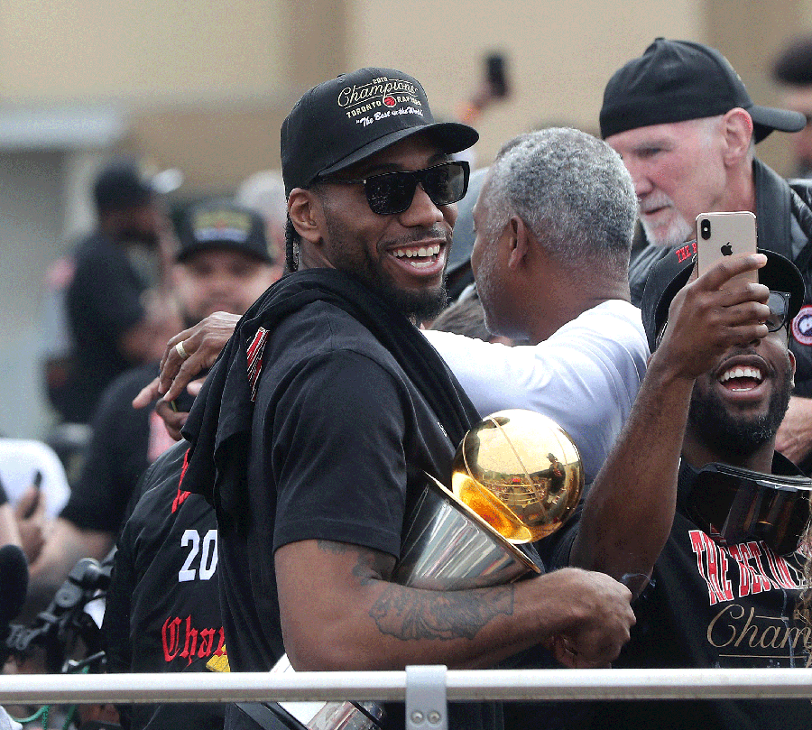 Kawhi Leonard on the Championship Parade route in Toronto holding his finals MVP trophy.