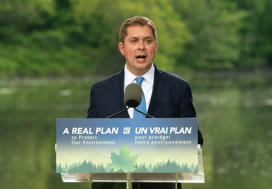 Andrew Scheer speaks at a podium that reads &quot;a real plan.&quot;