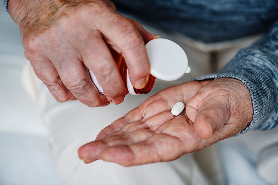 Man dispensing medication into his hand from pill bottle.