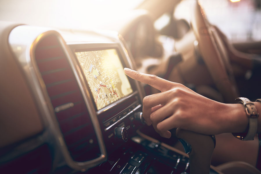A person touching the screen of a car's GPS with their finger.