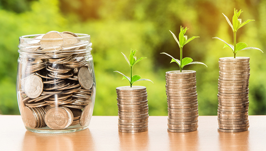 An image of coins in a jar and in stacks with little plants growing out of the top.