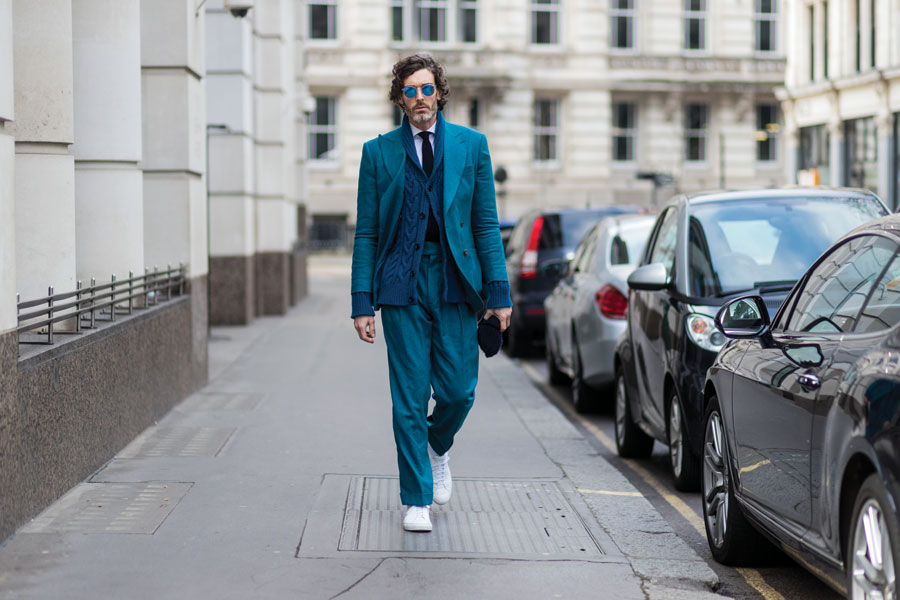 Man in aqua blue suit wearing white sneakers.