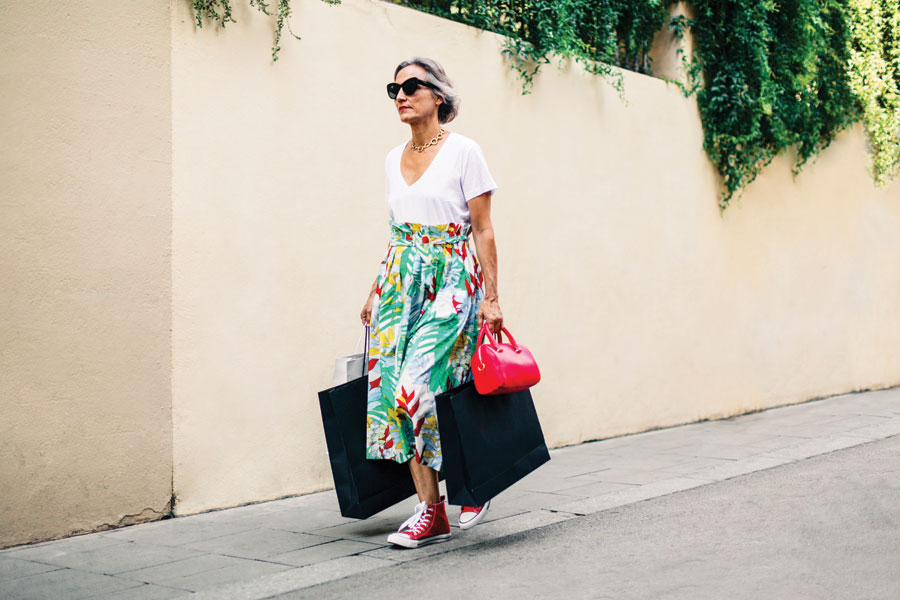Woman in bright coloured floral long skirt wearing red chuck sneakers.