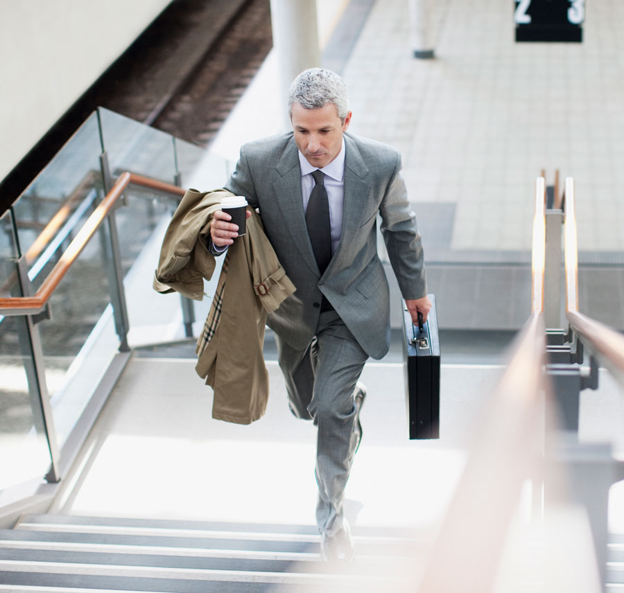 A businessman climbs the stairs up from a train platform