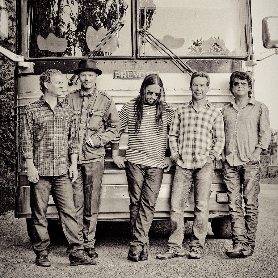 The Tragically Hip lined up in front of their tour bus.