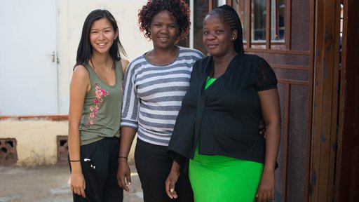 An Asian-American female stands outside in the sun with her friends in Botswana