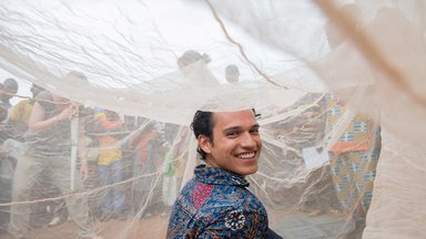 A Volunteer sits under a bed net