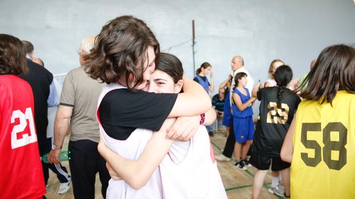Two basketball players embrace after an emotional win.