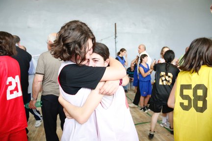 Two basketball players embrace after an emotional win.