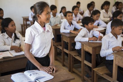Girl standing at her desk in a classroom in Cambodia.