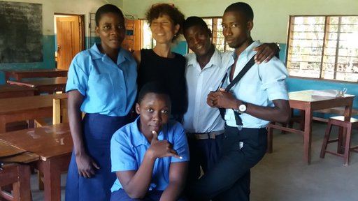An older Volunteer stands with her Malawian high school students