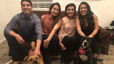 Fiorella's brother, sister, mom, and two dogs sit together on a couch