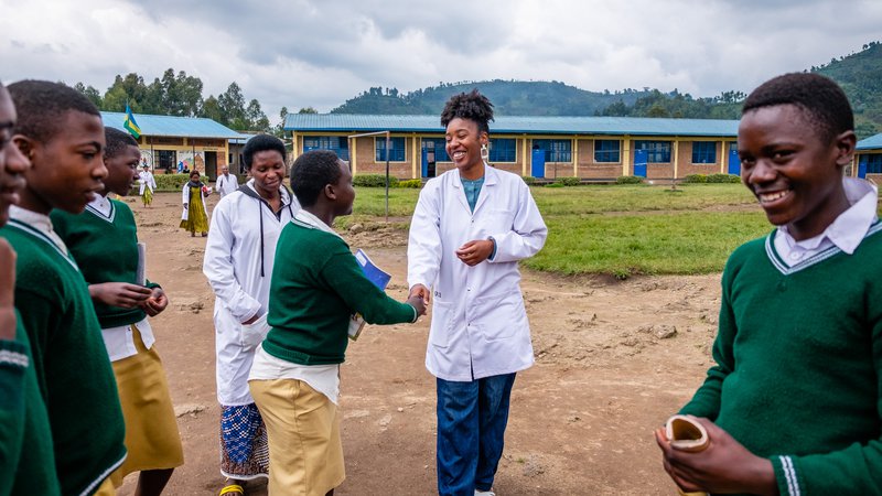 PCV Brina greets students in the school yard and shares a laugh and a smile