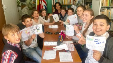 Older American woman with her Moldovan class as they show their projects.