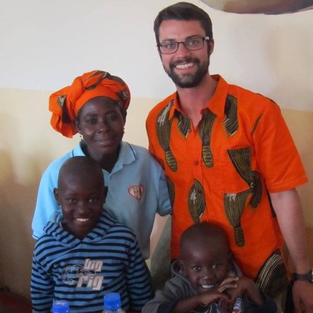 Peace Corps Volunteer Andrew Farr stands with a mother and her children.