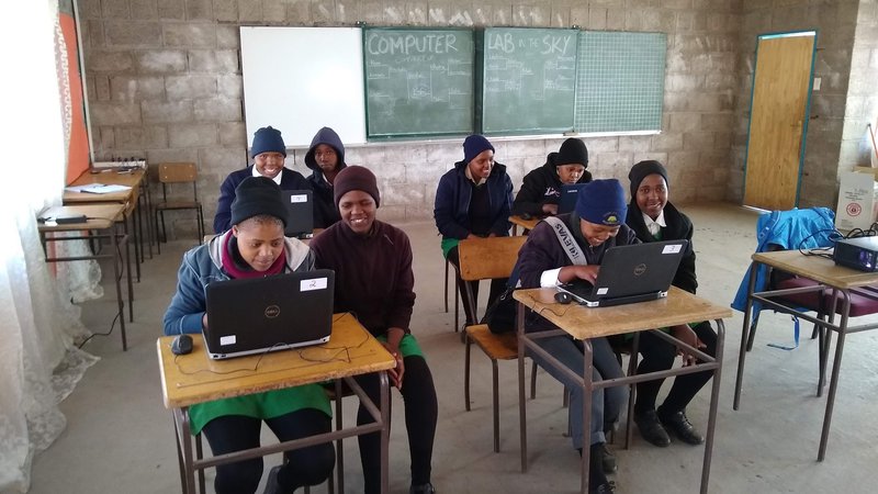Young African adults (Grade 11) in Western-style clothing work on computers in a classroom in Lesotho.