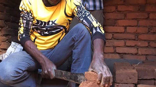 Volunteer Justin observes a cookstove being built
