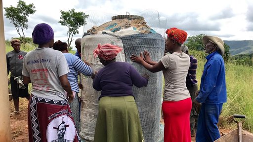 Community members securing concrete tank, so that it may dry.