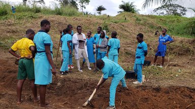 Students gather around teacher on the farm