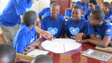 Volunteer David helps girls design on a healthy plateIMG_4478.JPG