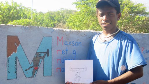 Student Joshua Tatangis holds his original artwork beside the completed "muscular mouse" he drew for the letter M in the alph