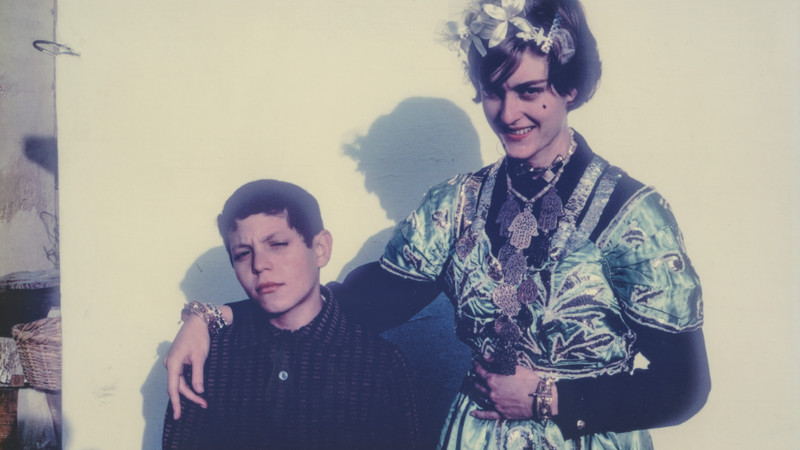 A young woman stands with her arm around a young boy.