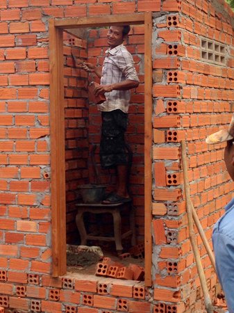 Cambodia: A community member lays bricks for the new latrines.