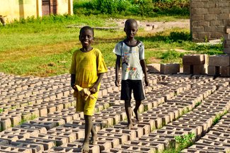 Local children walk across bricks made for the construction of the wall .jpg