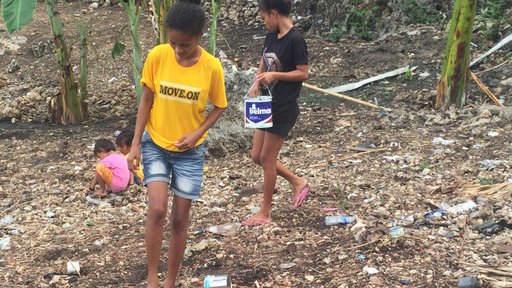 Two young women planting: one is looking for an open hole, the other covering up a hole with her foot.