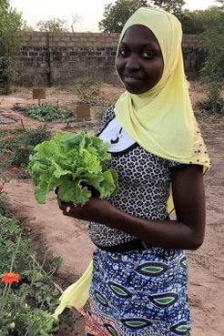A young girl holds up a crop proudly.
