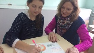Sandra Dale Woodruff reviews a Thanksgiving poster with her student