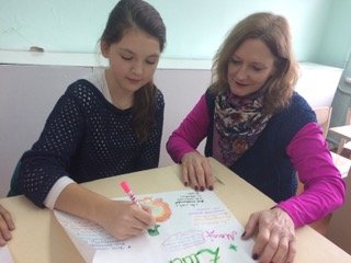 Sandra Dale Woodruff reviews a Thanksgiving poster with her student