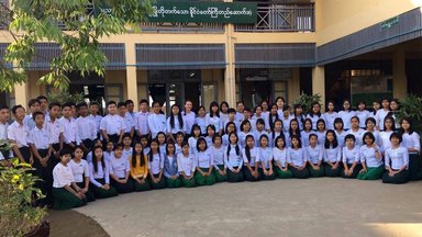 Many students, dressed in uniforms, pose for a picture.