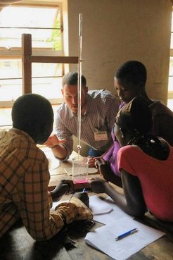 Travis and three students huddle around a table mid-lesson