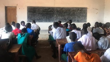 Students sit at desks looking at the blackboard in a classroom
