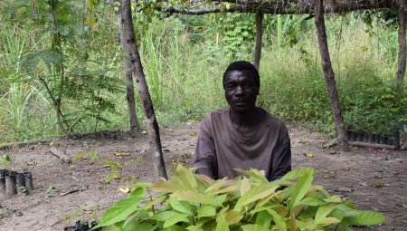Ada sits under some vines at his house.