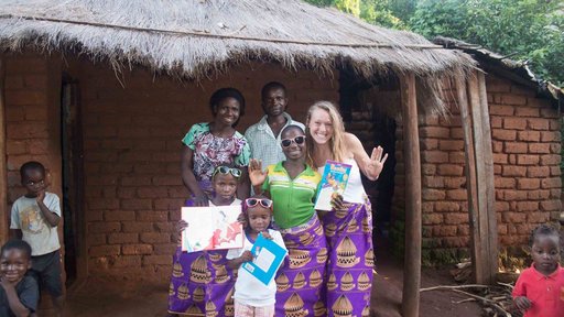 Health Volunteer Emma poses with her Malawain family--all wearing purple chitenje skirts.